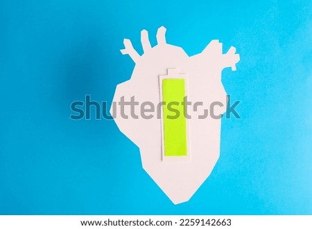 Paper cut Anatomical heart with full battery level on a blue background. Healthy heart concept