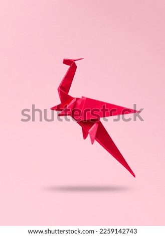Origami dragon levitating on a pink background