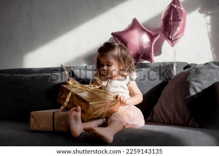 the two years gir sit in the sof at home and holding the present 