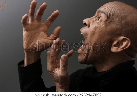 man shouting with anger on grey background with people stock photo	 