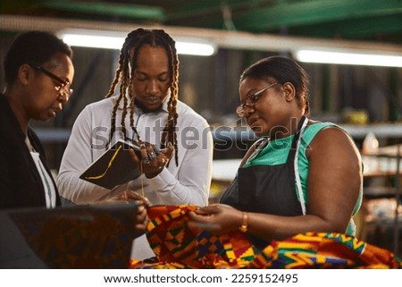 Textile industry employer and employees looking at laptop having a production meeting