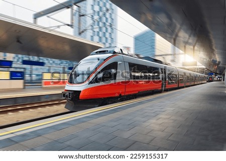Red high speed train in motion on the railway station at sunset. Fast modern intercity train and blurred background. Railway platform. Railroad in Austria. Commercial and passenger transportation Royalty-Free Stock Photo #2259155317