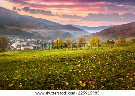 autumn landscape. village on the hillside. forest in fog on mountains at sunrise