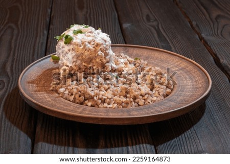 Meatball with cream sauce with buckwheat porridge on a plate. Background picture.