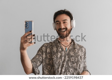Young gay latin man happy making a video call while talking on a wireless headset.