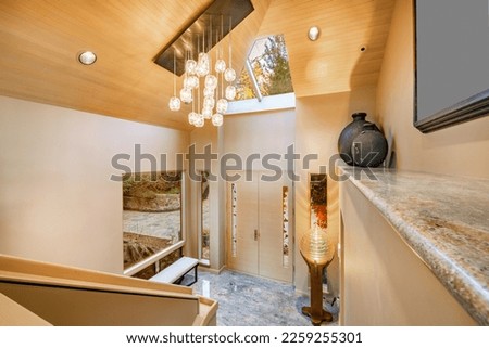 grand entry foyer of a luxury home with multi glass ball chandelier granite ledge skylight and large window and stairs Royalty-Free Stock Photo #2259255301