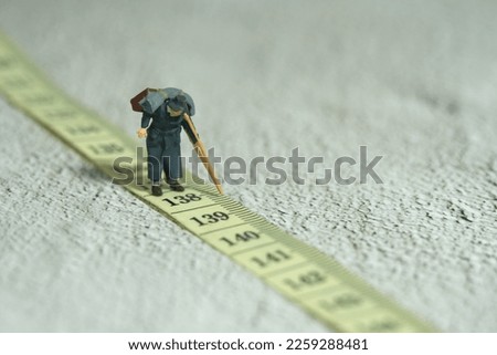Miniature people toy figure photography. An old men grandfather walking above measuring tape. Distance traveled concept. Image photo