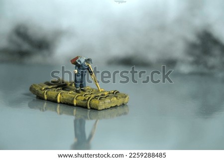 Miniature people toy figure photography. An old man refugees with crutch riding the raft alone, escape from conflict area to save place because of war. Image photo