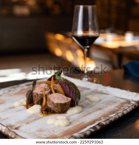 A glass of red wine in a restaurant with fillet steak cut into pieces