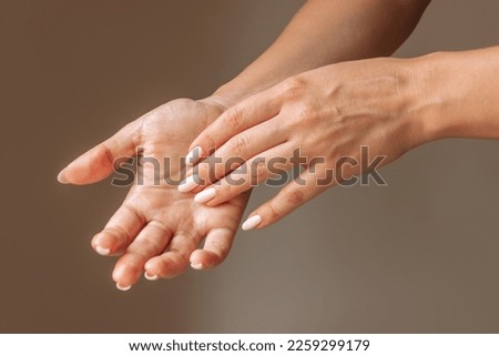 The problem of hyperteriosis. Cropped shot of a young woman touching her sweaty palms isolated on a brown background. Сlose-up of female hands. Hyperhidrosis, Increased sweating of the hands Royalty-Free Stock Photo #2259299179