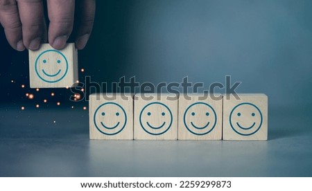 Happy face icons on wooden cubes, customer satisfaction or teamwork concept. Customer service evaluation and satisfaction survey concepts. Client's hand picked happy smile face symbol on wooden blocks
