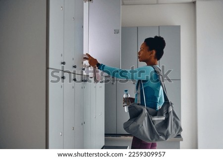 African American athletic woman preparing for sports training at gym's locker room. Copy space. Royalty-Free Stock Photo #2259309957
