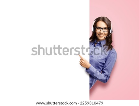 Contact Call Center Service. Customer support, sales agent. Caller answering phone operator. Smiling woman in glasses, headset hold, peep, stand behind white blank signboard, rose pink background