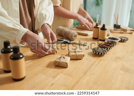 Hands of woman tying knot on handmade soap bar in craft paper Royalty-Free Stock Photo #2259314147