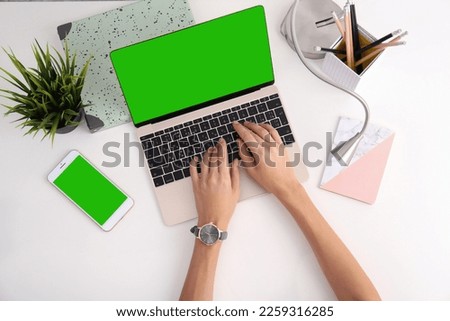 Young woman using laptop at white desk, top view. Device display with chroma key