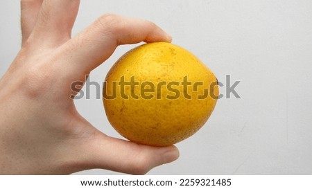 A Finger Hand Holding A Beautiful Textured Skin Of Ripe Fresh Healthy Round Yellow Lemon. Isolated In Front Of White Background. 3D HD RAW JPEG JPG Image Picture Photography. Original Natural Object.