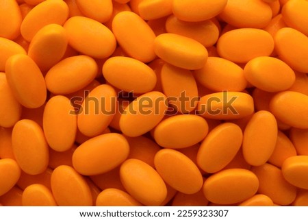 Tasty orange dragee candies as background, top view Royalty-Free Stock Photo #2259323307