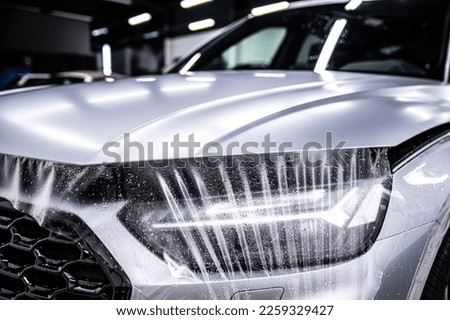 Protection of hood and front of the car with a colorless ppf protective film.  Royalty-Free Stock Photo #2259329427