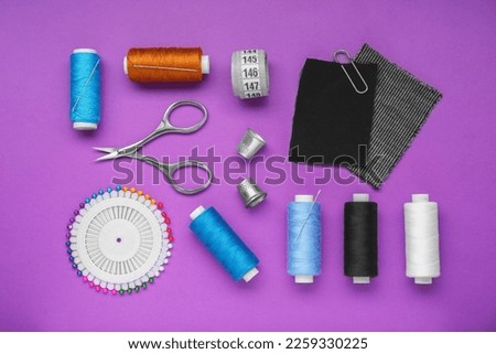 Flat lay composition with thimbles and different sewing tools on purple background Royalty-Free Stock Photo #2259330225