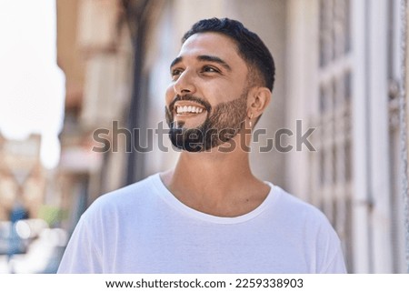 Young arab man smiling confident looking to the side at street Royalty-Free Stock Photo #2259338903