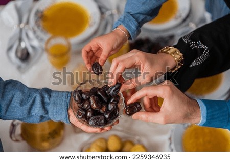 Happy Muslim family having iftar dinner to break fasting during Ramadan dining table at home group of Islamic people eating a healthy food dates together sharing and giving. Royalty-Free Stock Photo #2259346935