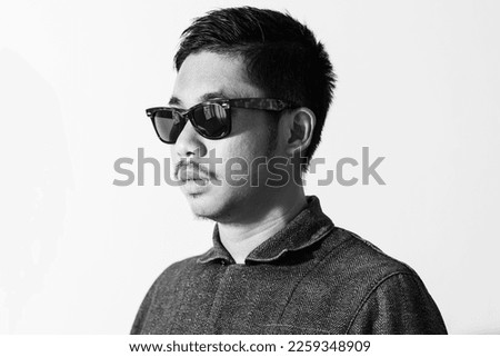Black and white  image of Asian man wearing sunglasses on white background.