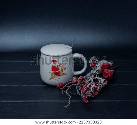 Decor for backgrounds and compositions. White cup with red handle. Branches of decorative greenery. Black background. New Year's composition.