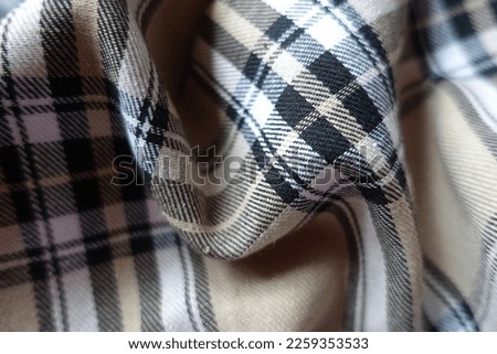 Light beige, black and white cotton flannel tartan fabric in soft folds