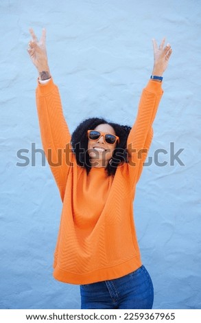 Carefree, peace sign and trendy woman on a wall in the city for cool energy, playful and happy with sunglasses. Comic, fun and crazy stylish girl with a hand emoji for freedom and funky smile