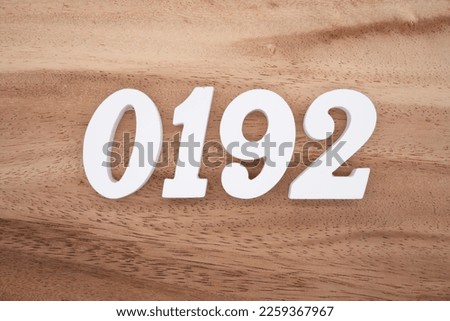 White number 0192 on a brown and light brown wooden background.