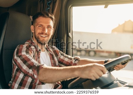 Professional middle aged truck driver in casual clothes driving truck vehicle going for a long transportation route. Royalty-Free Stock Photo #2259376559