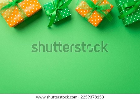Saint Patrick's Day concept. Top view photo of green and orange gift boxes with ribbon bows on isolated green background with copyspace