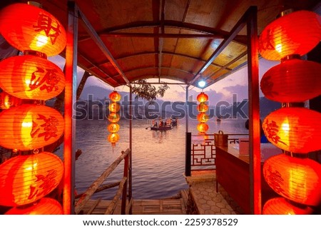 The Pier for tourists to ride chiness boats on the lake at Ban Rak Thai village, Mae Hong Son province, Thailand. Chinese characters on red lantern - Translated text means happy, lucky, wealthy Royalty-Free Stock Photo #2259378529