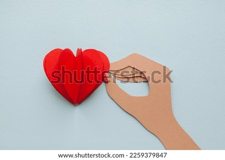 Handmade cutout heart in hand with manicure on blue background. Pop art and cartoon comic style. 