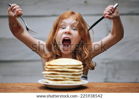 Young crazy girl eating a stack of pancakes. 