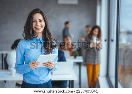 Waist up portrait modern business woman in the office with copy space. Female executive wearing businesswear standing outside modern meeting room and checking data on tablet. Royalty-Free Stock Photo #2259403041