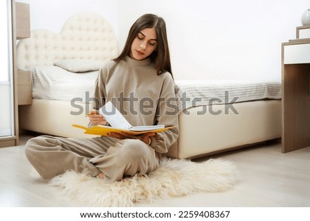 Teen girl sits near the bed and journal in a notebook, keeps a diary book Royalty-Free Stock Photo #2259408367