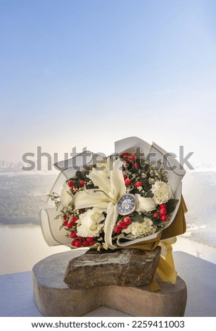 Analog pocket watch on the middle of the Bouquet of flowers placed on stone boulder and timber on the room balcony. Symbol of Romantic forever love, Free space for text.