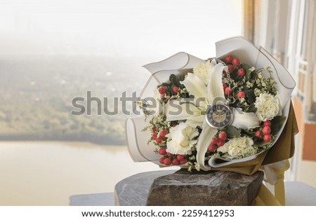 Analog pocket watch on the middle of the Bouquet of flowers placed on stone boulder or black rock on the room balcony. Symbol of Romantic forever love, Free space for text.