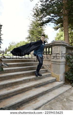 portrait of handsome brunette male model wearing fantasy medieval prince costume, romantic silk shirt. Wandering around historical castle location background with stone staircase.