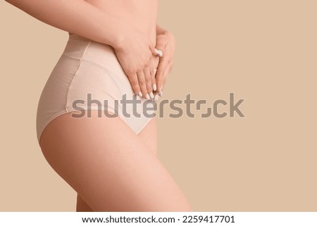 Young woman in menstrual panties on beige background, closeup Royalty-Free Stock Photo #2259417701