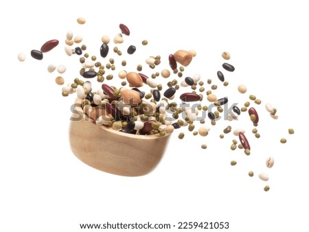 Mix beans fall down explosion, several kind bean float explode in wooden bowl. Dried white green red soy black peanut mixed beans splash throwing in Air. White background Isolated high speed shutter