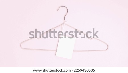 Creative flat lay hanger with white paper label pink background. Clothing tag, label blank mockup template. Sale discount store promo shopping concept. Top view. Copy space