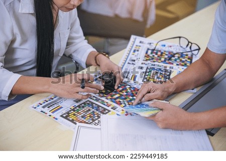 Crop image of worker checking print quality of media graphics proof print in printing industry. Selected focus