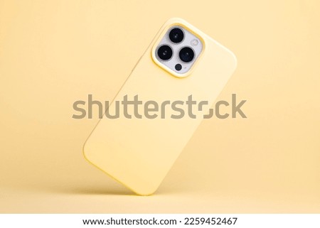 iPhone 13 and 14 Pro Max in yellow banana soft silicone case falls down back view, phone case mockup in monochrome colours isolated on yellow background