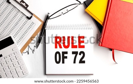 RULE OF 72 text on a notebook with clipboard and calculator on white background Royalty-Free Stock Photo #2259456563
