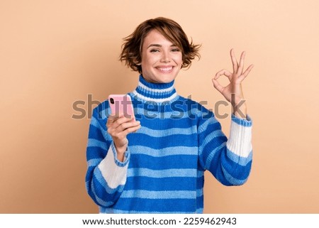 Portrait of influencer blogger girl promoter recommend new app for remote chatting without wifi okey symbol isolated on beige color background