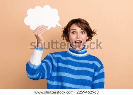 Portrait of astonished cheerful person hand hold empty space paper cloud shape isolated on beige color background