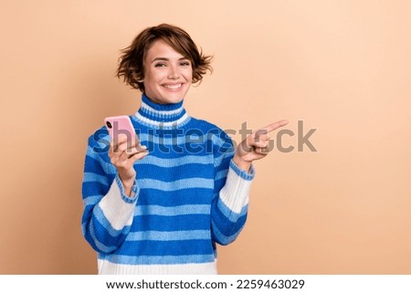 Photo of pretty cheerful lady hold telephone direct finger empty space isolated on beige color background