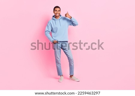 Photo of positive satisfied stylish man wear trendy blue comfort street style outfit thumb up empty space isolated on pink color background